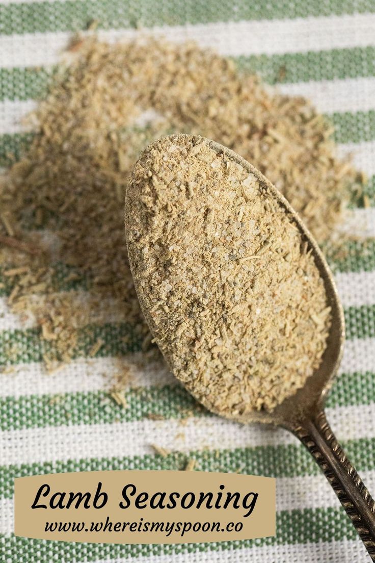 a wooden spoon filled with dried herbs on top of a green and white checkered table cloth