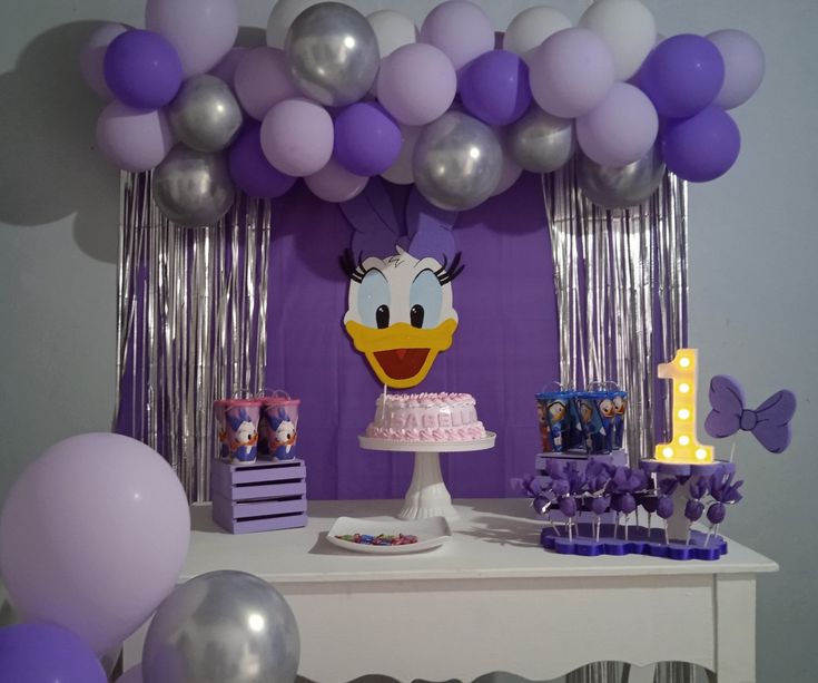 a table with balloons and decorations for a first birthday