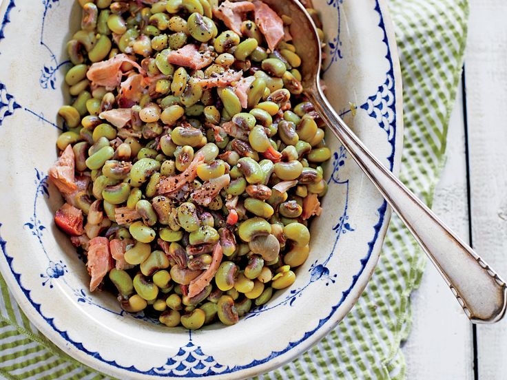 a bowl filled with peas and ham on top of a table