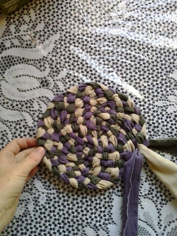 a person is holding a piece of woven material on a doily covered tablecloth