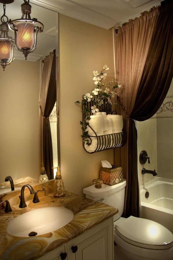 a bathroom with a toilet, sink and bathtub next to a window covered in brown drapes