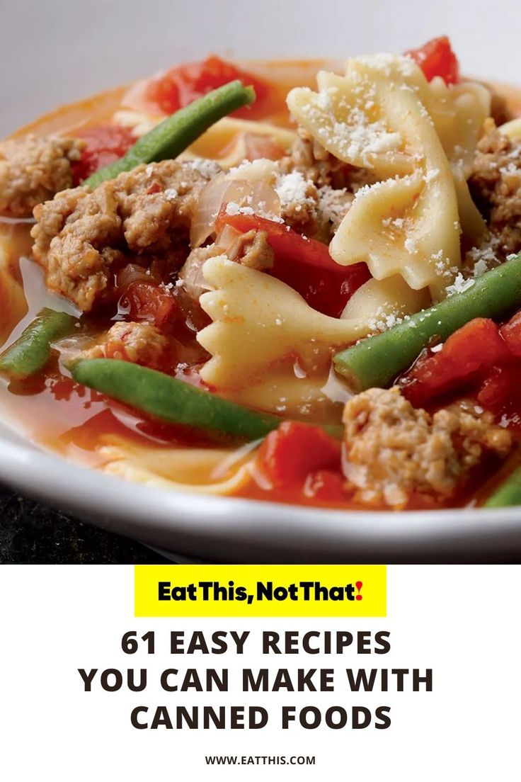 a white bowl filled with pasta and meat next to green beans on top of a table