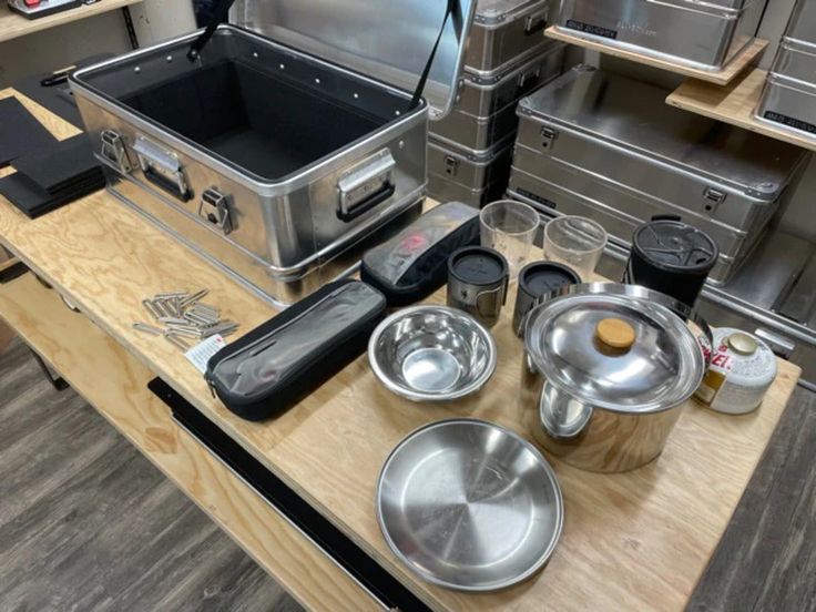 an assortment of cooking utensils on a wooden table in a kitchen with stainless steel appliances