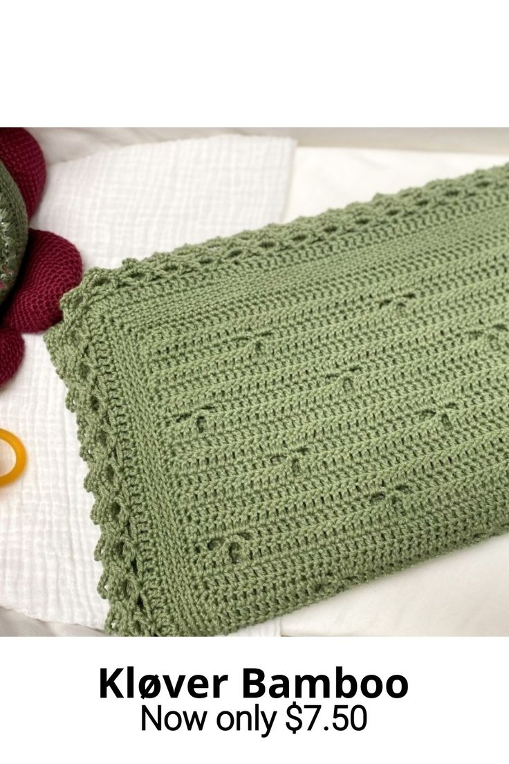 a green crocheted blanket sitting on top of a bed next to a pair of scissors