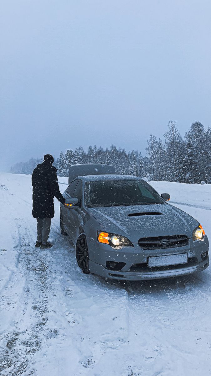 a person standing next to a car in the snow