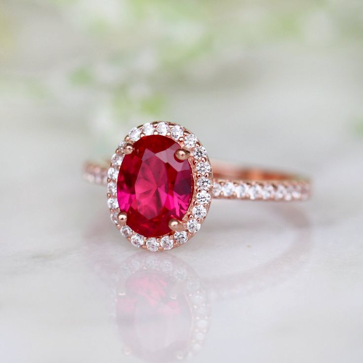 a close up view of a ring with a red stone in the center and white diamonds around it