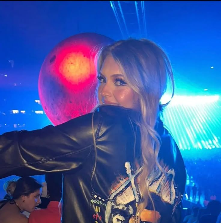 a woman in black leather jacket standing next to a red ball