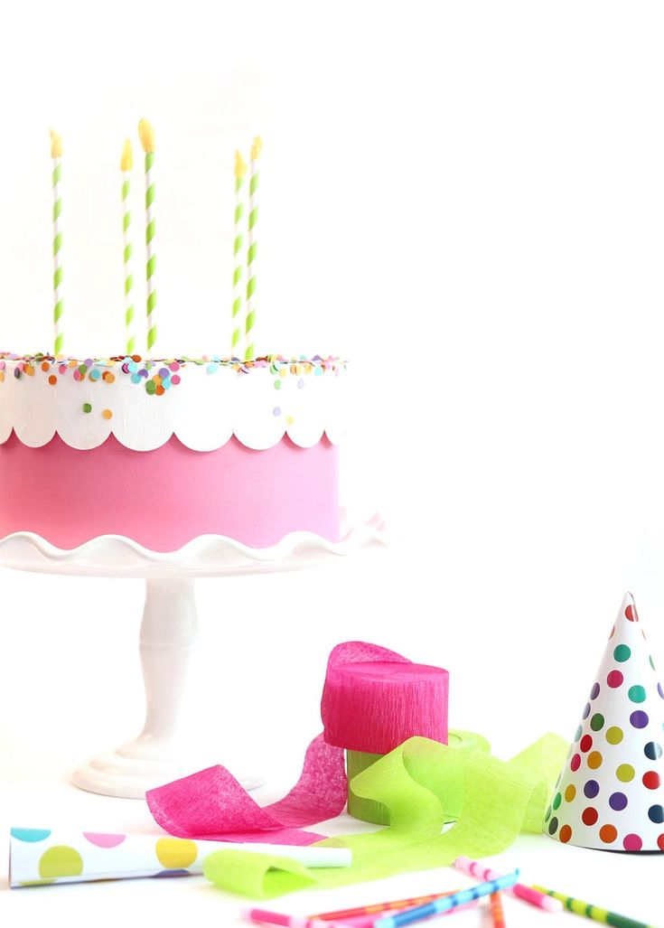 a birthday cake with lit candles on it and confetti around the cake top