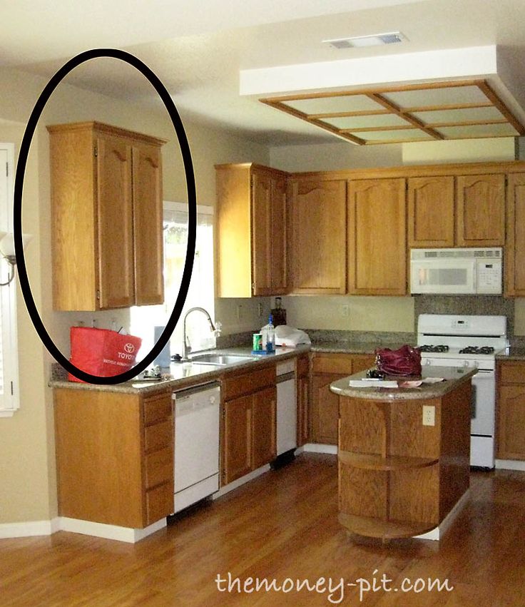 an empty kitchen with wooden cabinets and white stove top oven in the center, surrounded by wood flooring