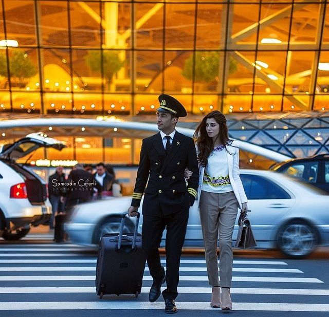 a man and woman are walking across the street with suitcases in hand while cars pass by