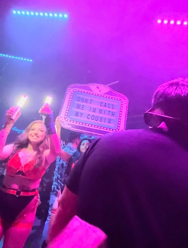 a group of people holding up signs in the air at a concert with lights on