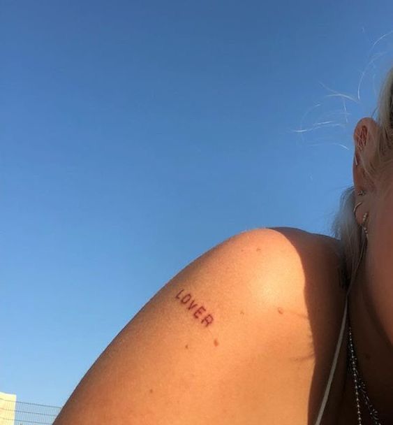 a close up of a person with tattoos on her arm and shoulder, looking at the camera