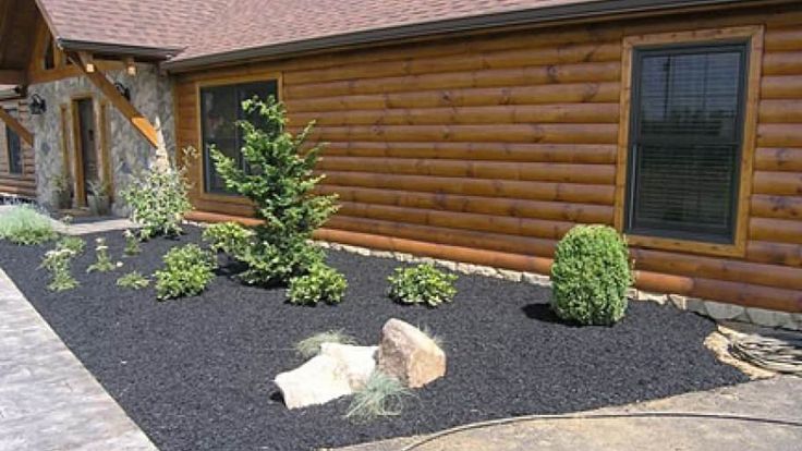 a log house with landscaping and rocks in the front yard