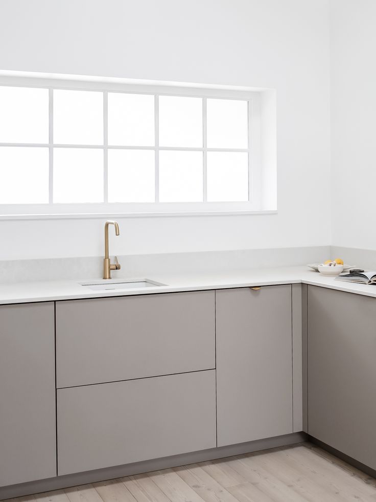 an empty kitchen with white walls and wood flooring is pictured in this image, there are no people or objects on the counter