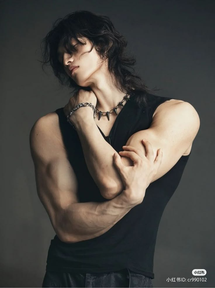 a man with long hair wearing a black shirt and chain around his neck, posing for a photo