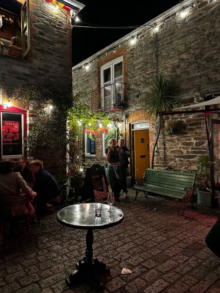 people are sitting at tables outside in the evening