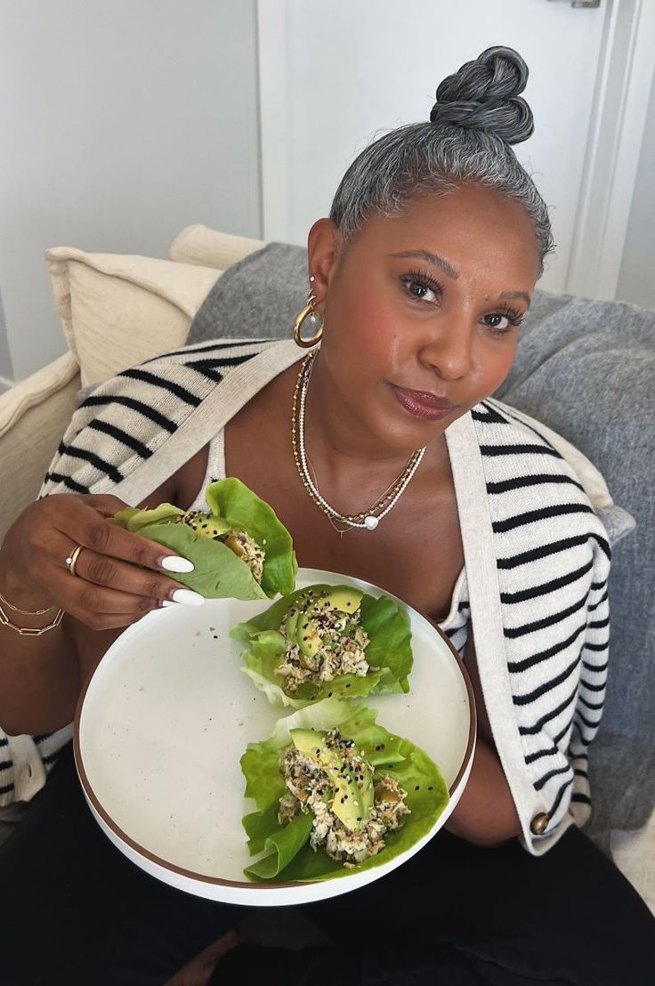 a woman sitting on a couch holding a plate with lettuce leaves in it