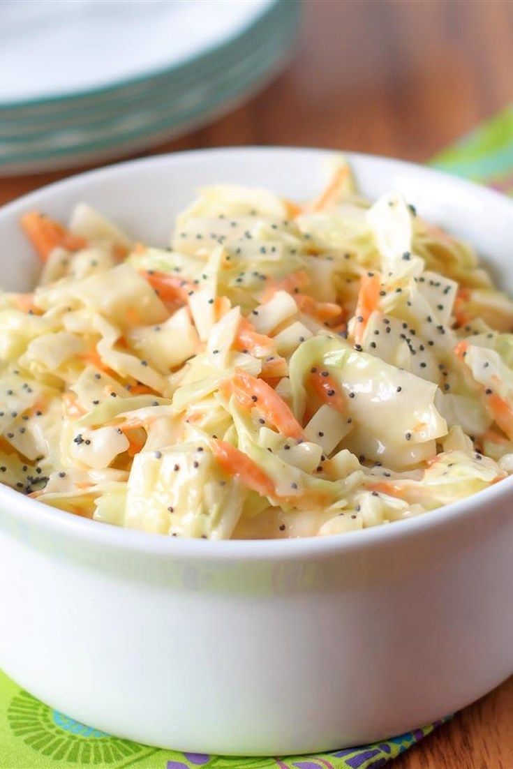 a bowl filled with coleslaw and carrots on top of a wooden table