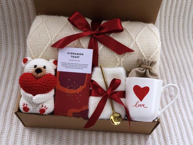 a teddy bear and two mugs in a box with a red ribbon on it