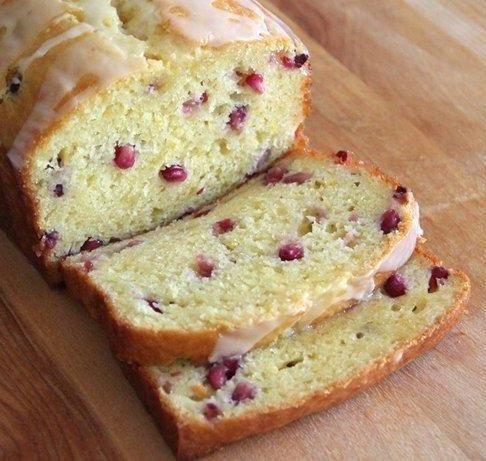 a loaf of cranberry orange bread with icing on a wooden cutting board