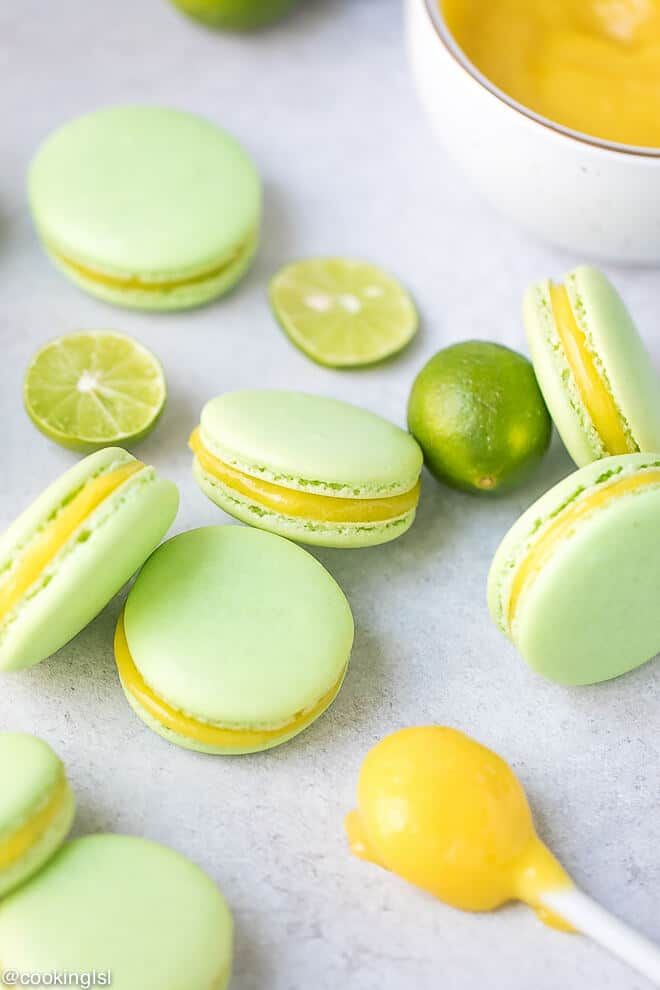 green and yellow macaroons with limes next to them on a counter top