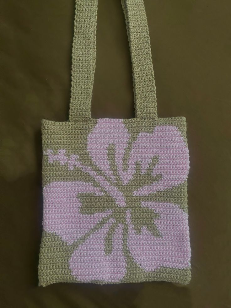 a crocheted bag with pink and green flowers on the front, hanging from a hook