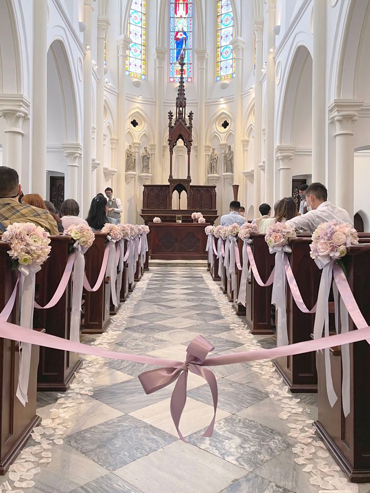 the aisle is decorated with pink ribbon and flowers