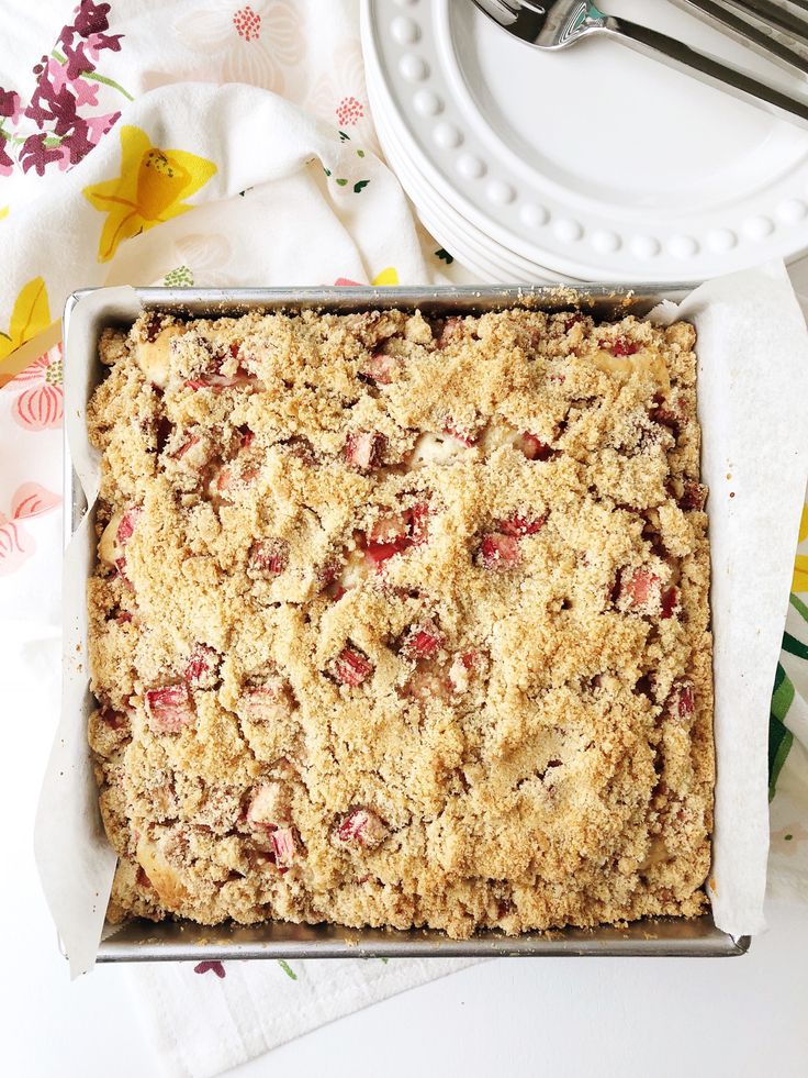 a freshly baked strawberry crumbled dessert in a pan on a table with flowers