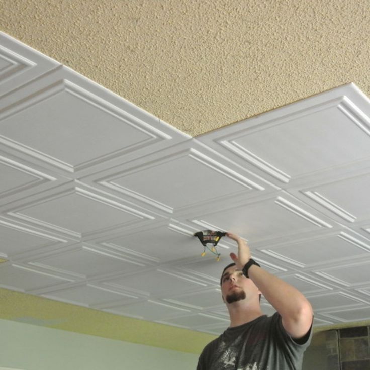 a man that is standing up with a remote in his hand and some lights on the ceiling