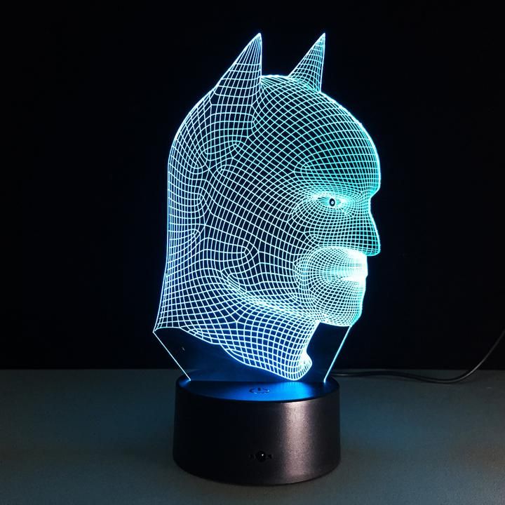 a 3d image of a batman mask is shown on a black surface with a blue light behind it