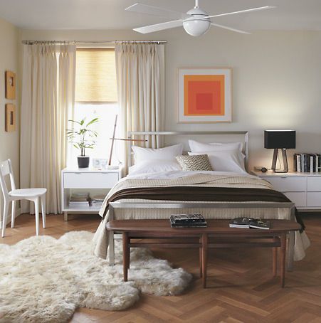 a bed room with a neatly made bed next to a window and a rug on the floor