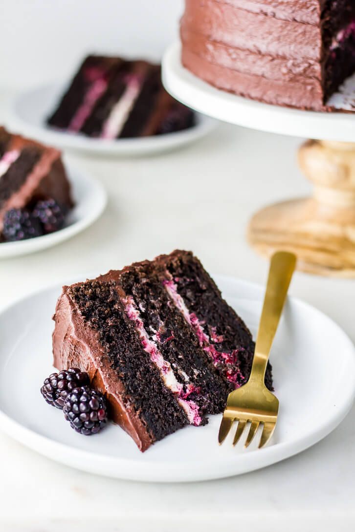 a slice of chocolate cake with raspberry frosting on a plate next to a fork