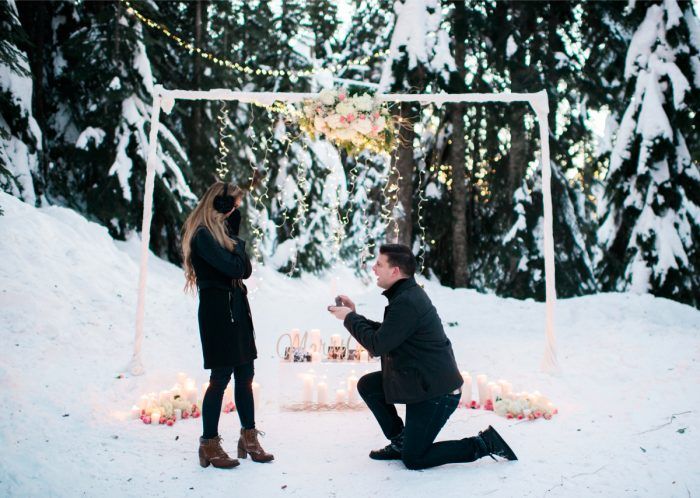 a man kneeling down next to a woman in the snow