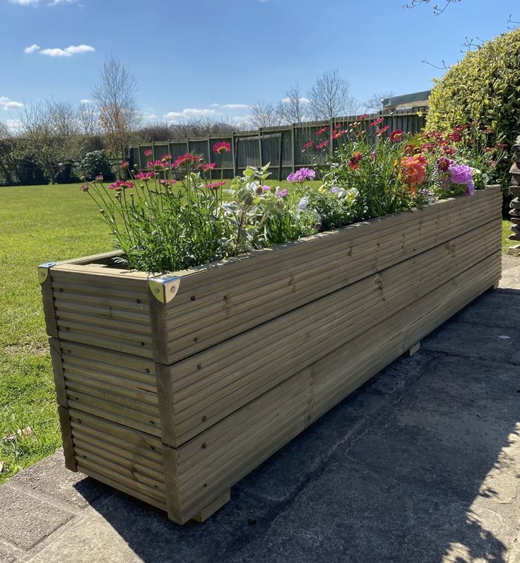 a large wooden planter filled with lots of flowers