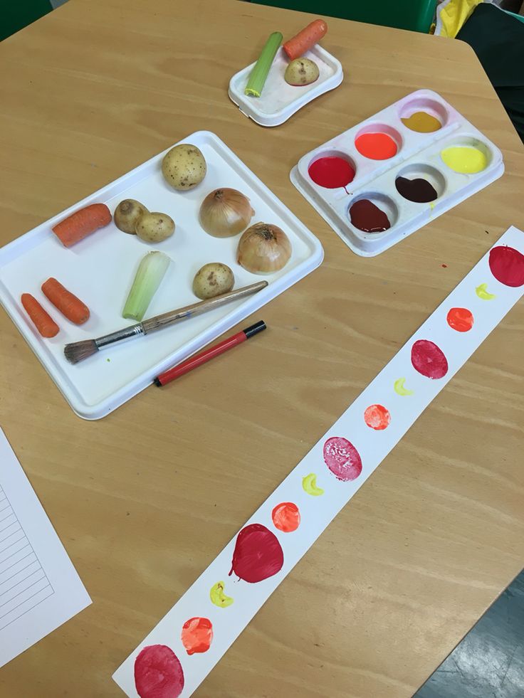 a wooden table topped with trays of food next to paint and paper on top of it