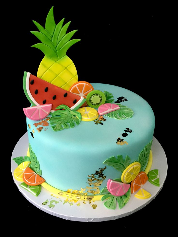 a blue cake decorated with fruit and leaves