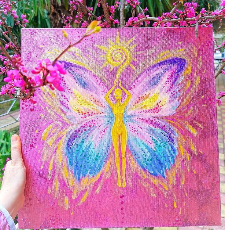 a person holding up a painting in front of some pink and purple flowers with a butterfly on it