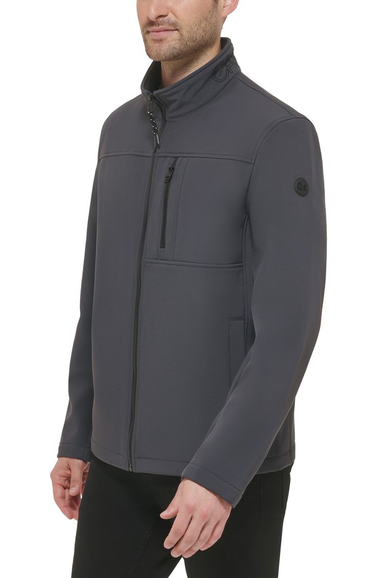 A water resistant construction, zip through collar and multiple pockets offers versatility to this sporty jacket. Zip through stand collar Long sleeves CK logo detailing Zipper front Zipper chest and dual side welt pockets Solid Woven Shell face: 94% polyester, 6% spandex; Shell back: 100% polyester Machine wash cold Imported Model stats: 6'1" height, 32" waist. Model is wearing size M. Functional Fleece Jacket With Zipper For Outdoor Activities, Solid Fleece Jacket With Zipper For Outdoor, Solid Functional Half-zip Outerwear, Functional Solid Color Half-zip Outerwear, Functional Sports Outerwear With Zipper Closure, Solid Color Functional Half-zip Outerwear, Sporty Jacket, Soft Shell Jacket, Front Zipper