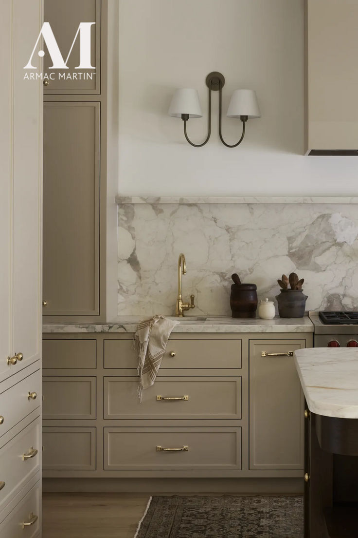 a kitchen with marble counter tops and gold pulls on the cabinet doors, along with two lamps