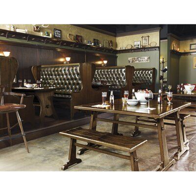 an empty restaurant with wooden tables and benches in front of the counter area, along with wine glasses on the table