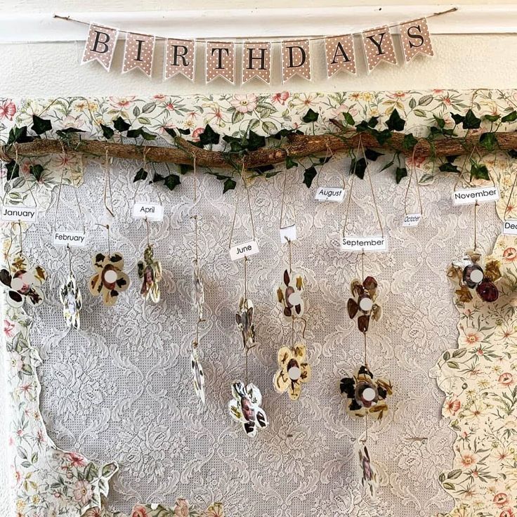 a birthday banner hanging on the side of a wall next to flowers and ribbons with name tags attached