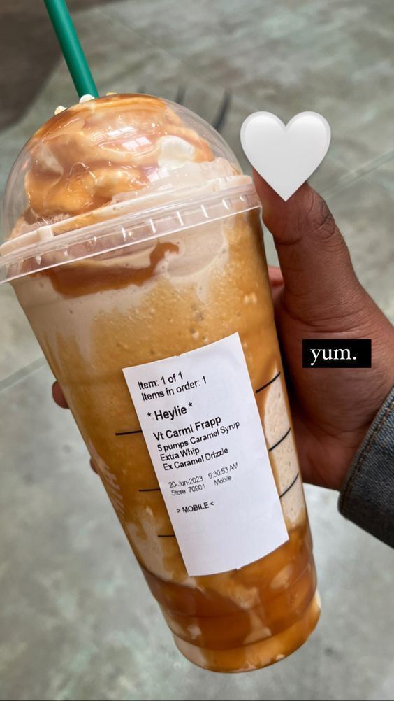 a person holding up a drink with a heart shaped foam on it's side