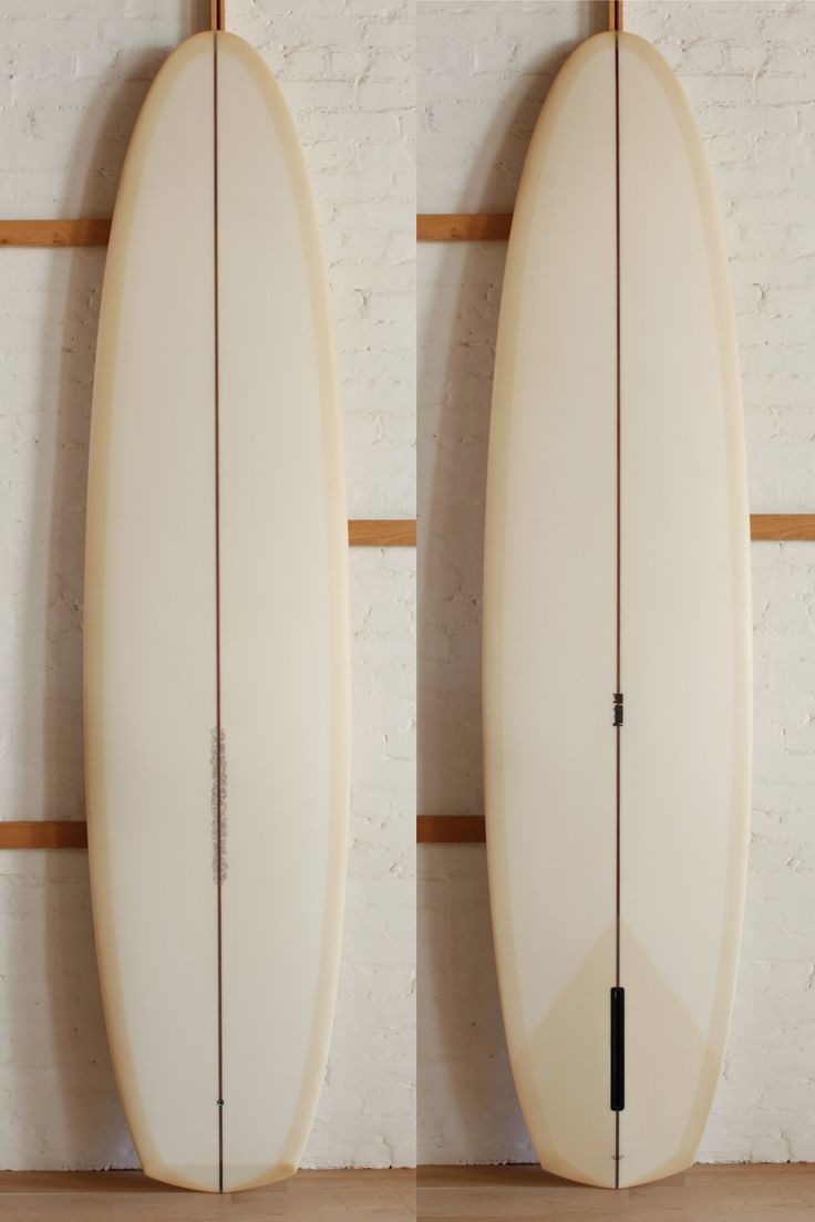 two white surfboards against a brick wall with wood slats on the bottom and bottom