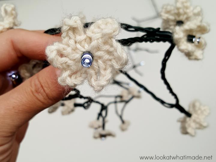 a crocheted flower is being held by someone's hand with beads on it