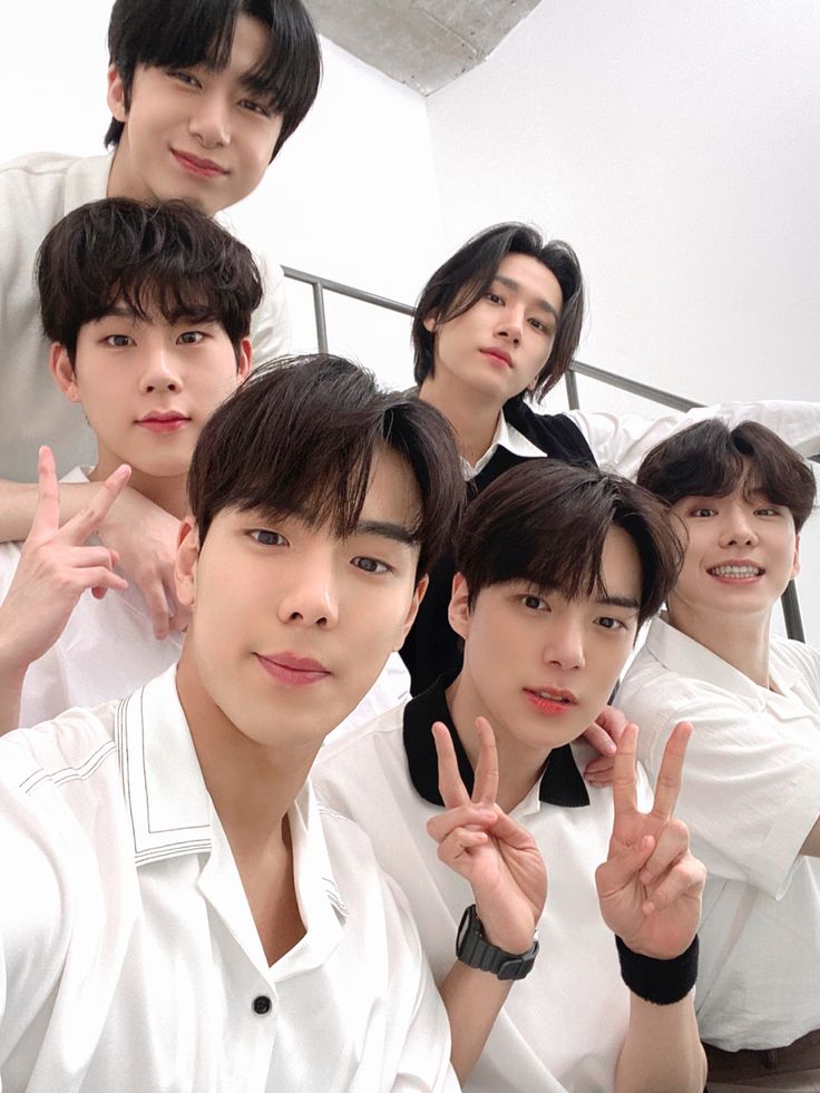 group of young men posing for the camera with their fingers in the shape of two peace signs