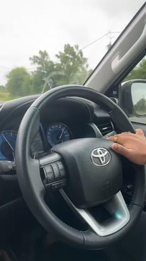 a woman driving a car with her hand on the steering wheel and dashboard controls in front of her