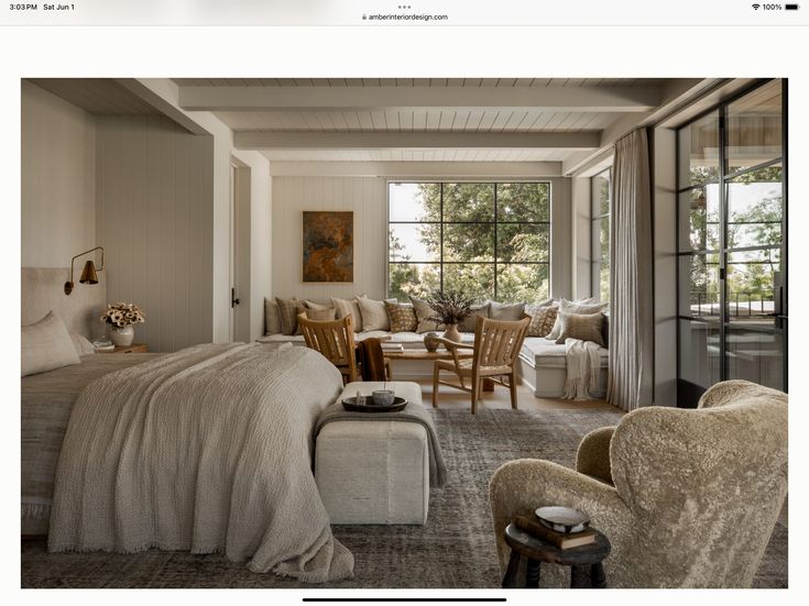 a bed room with a neatly made bed next to two chairs and a table in front of a window