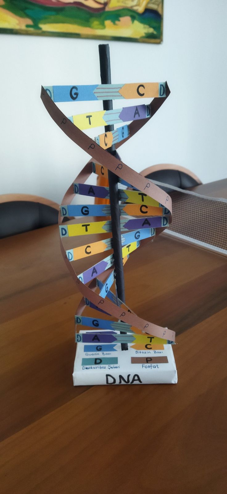 a wooden table topped with a book and a model of a strand of colorful paper