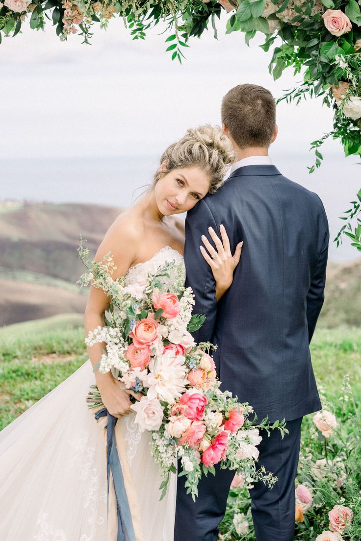 a bride and groom standing under an arch with flowers