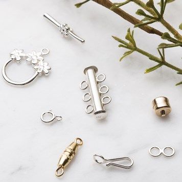 several different types of metal objects on a white surface next to some plants and flowers